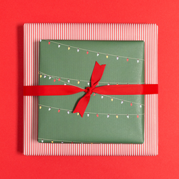 Green wrapping paper with fairy lights pattern, tied with a red ribbon.