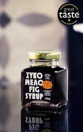 Premium fig syrup in a glass jar with a green lid. The syrup has a dark, rich color and is surrounded by some fig slices.