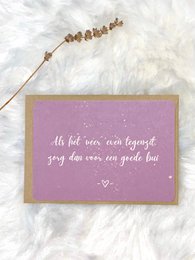 A pink greeting card with a handwritten message in German that translates to "As long as you have a good mood, you can get through everything." The card is decorated with a gold string and beads.