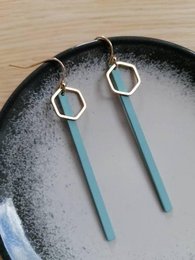 Statement earrings with long, thin teal-colored bars and hexagonal gold-colored accents.