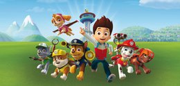 The image shows a group of cartoon characters from the Paw Patrol TV show. They appear to be standing in a grassy outdoor setting with mountains in the background. The characters include the main pups - Chase, Marshall, Rubble, Skye, Rocky, and Zuma - as well as the human character Ryder. The image suggests this is a product related to the Paw Patrol franchise, likely wall art or a poster.