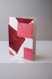 A folding card with a geometric pattern in shades of red and pink, featuring a heart-shaped design.
