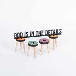 Black and white text-based statue with the quote "God is in the details" on a minimalist desk setup.