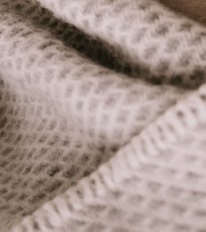 Large grey woolen blanket or throw with a textured knit pattern.