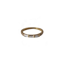 A delicate gold-toned ring with a row of small stones, suitable for stacking with other rings.