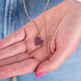A gold chain necklace with a heart-shaped pendant adorned with red crystals or rhinestones. The pendant appears to be a charm or decorative element that can be attached to the necklace.