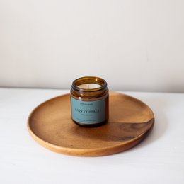  Cozy cottage scented candle in a glass jar with a gold lid. The candle has a warm, comforting fragrance perfect for fall.