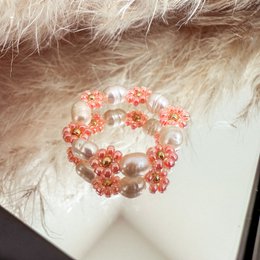 Delicate glass bead flower ring in apricot and pearl colors, perfect for stacking with other rings.