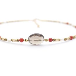  A necklace with a smoky quartz pendant and coral beads, featuring a delicate, natural-looking design.