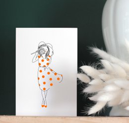 Card Mireille - Kobieta w białym kapeluszu i sukience z czerwonego groszku pachnie kwiatem