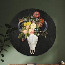 A round wall decor featuring a floral arrangement with a skull motif. The image shows a vibrant bouquet of colorful flowers arranged around a white animal skull against a dark background.