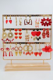 Assortiment de 15 paires de boucles d'oreilles de couleur rouge assorties, en acier inoxydable, montées sur un présentoir métallique avec un socle en bois.