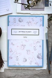 Soft pink notebook with puff blue framing, featuring a delicate floral pattern design.