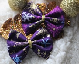 Purple and gold glittery hair barrettes with snowflake designs, perfect for the holiday season. Includes details on the materials, style, and shape of the accessories.