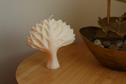 Tall, round, white candle with a tree of life design. Made of wax material.