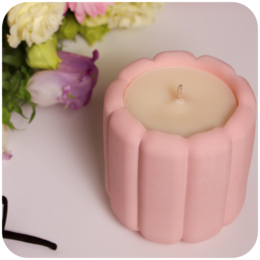 A round, tall, pink scented candle with a floral design.