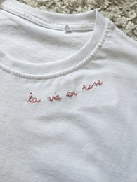  White t-shirt with embroidered 'La vie en rose' text, short sleeves, suitable for women.