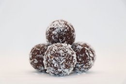 Raw cocoa energy balls in bulk, 1 kg. Spherical shape, dark brown color, coated in shredded coconut.