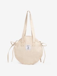 Paulette round shopping bag, a beige canvas tote bag with drawstring closure and leather accents, suitable for everyday use.