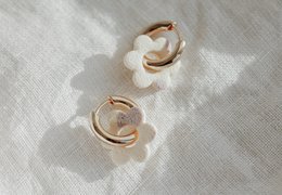 Elegant gold-tone hoop earrings with delicate white floral accents, perfect for adding a touch of feminine style to any outfit.