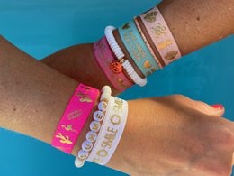 Colorful elastic bracelets with tropical palm tree and pineapple designs. Includes a variety of vibrant colors and patterns.