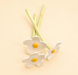 Handmade ceramic white daisy flowers with yellow centers, green stems, decorative floral arrangement