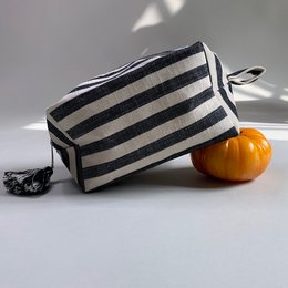 A black and white striped cosmetic bag with a tassel zipper pull.