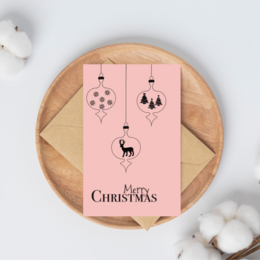 Ornament-shaped Christmas card with pink background, featuring silhouettes of snowflakes, trees, and a deer.