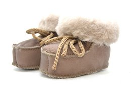  "Cozy kids slippers with genuine leather and wool fur trim, brown and natural colors, soft warm footwear."