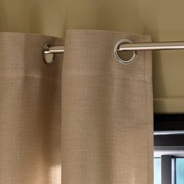 Beige curtains with eyelets, available in multiple sizes for a blackout effect.