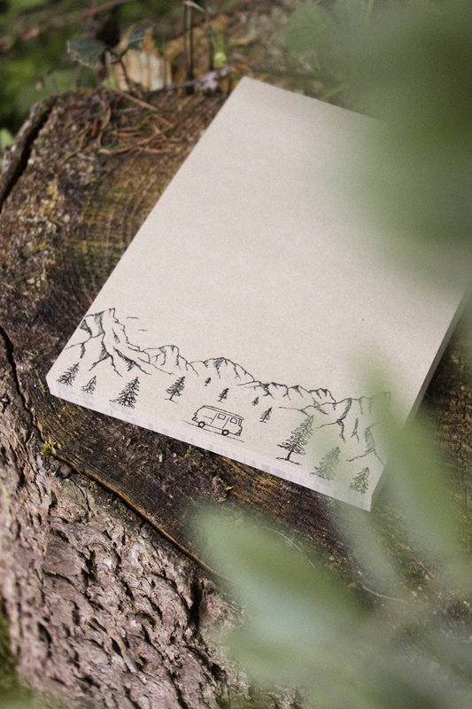 Camper con blocco note in carta erba in montagna