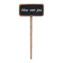  A small chalkboard sign on a wooden stick, displaying the text "Hou van jou" which means "I love you" in Dutch. The sign is placed in a small white pot containing a green plant.