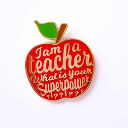 Red apple-shaped pin with text "I am a teacher, what is your superpower?". The pin features a vibrant red apple design with green leaf accents, and the text is displayed in a bold, playful font.