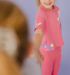 Hot pink kids t-shirt with star and unicorn graphic, paired with patterned pants.