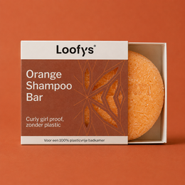 A solid, red shampoo bar with a circular label featuring the brand name "Loot's". The bar is placed on a white, fluffy towel or cloth.