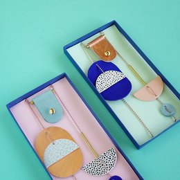 Porcelain wall jewelry in copper with stripes and kobalt with dots, featuring abstract shapes and colors.