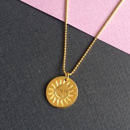 A golden sun-shaped charm necklace with a delicate chain.