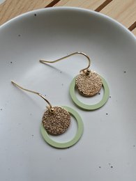 Pastel green-gold statement earrings with glittery gold accents and circular shapes.