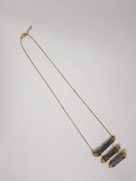 Delicate gold-tone necklace with three cylindrical charms in varying shades of gray.