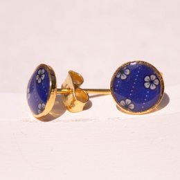 Stud earrings with a round, blue enamel design featuring a floral pattern. The earrings have a gold-tone metal setting.