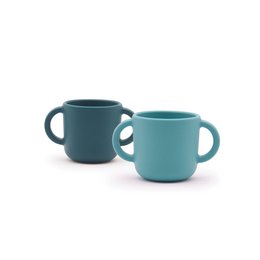 "Two teal-colored training cups with handles, suitable for children's use. The cups have a simple, minimalist design and appear to be made of a durable material."