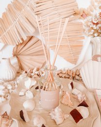 Beige reed diffuser with natural dried flowers, coastal aesthetic, warm neutral tones, decorative home fragrance.