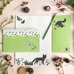 A stationery set featuring a forest theme, including envelopes with a green background and black silhouettes of animals and butterflies.