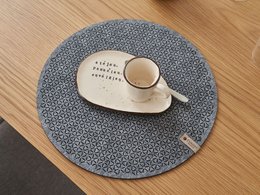 Round grey felt placemat with a textured pattern, suitable for use with a cup or other tableware.