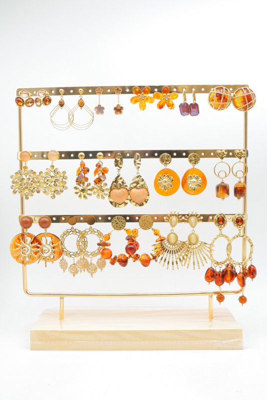 Présentoir en métal doré sur socle en bois, comprenant un lot de 16 paires de boucles d'oreilles déjà installées.
