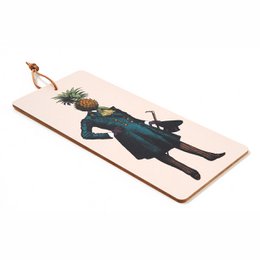 Rectangular wooden cutting board with a silhouette of a person wearing a long coat and holding a pineapple on their head.