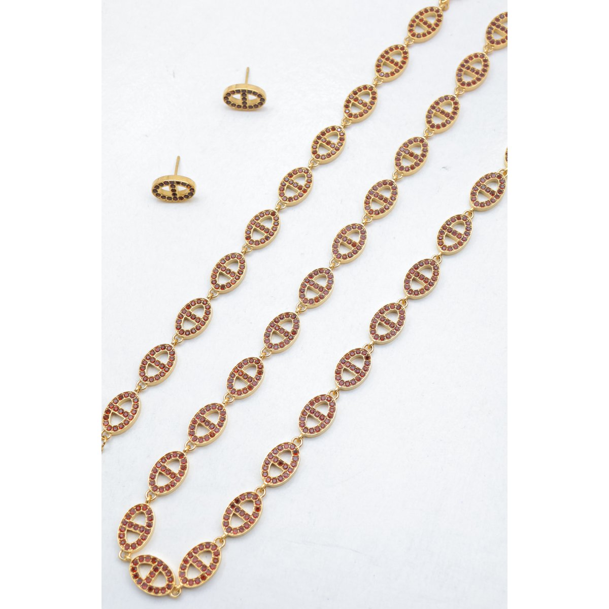 Ensemble assorti comprenant un collier, un bracelet en chaîne et une paire de boucles d'oreilles puces. Chaque bijou est composé d'une succession de maillons en forme de maille marine entièrement pavés de petits strass scintillants.