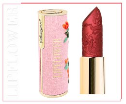  A vibrant red lipstick with a floral pattern on the packaging. The lipstick appears to be a vegan and titanium dioxide-free formula.