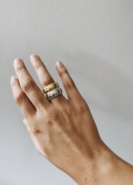 Gold statement ring with a bold, modern design. Features a rectangular shape and a sleek, minimalist style.