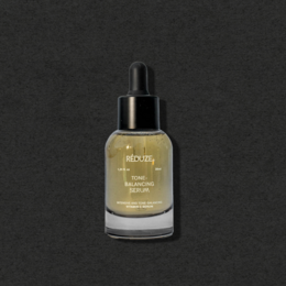Tone-balancing vitamin C serum in a glass bottle with a dropper. The serum has a golden yellow color.